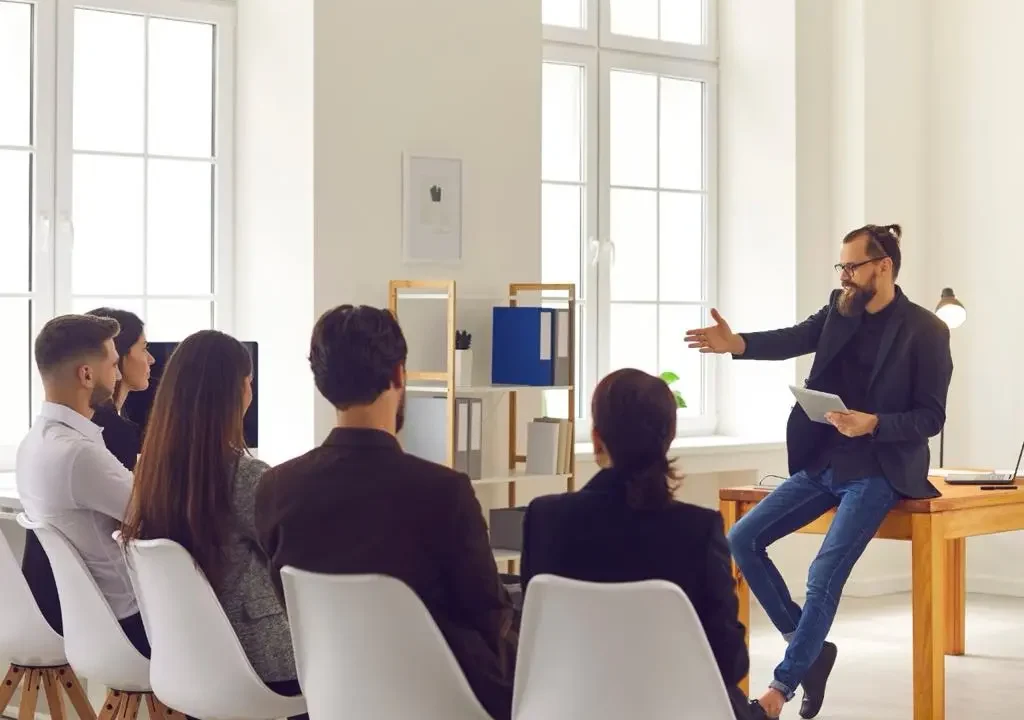 ტრენერი ატარებს სემინარს მცირე ჯგუფისთვის ოფისურ გარემოში.